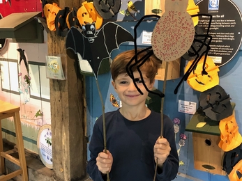 young boy holding up halloween craft of a bat and a spider