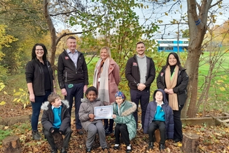 Group of school children and adults posing for photo in woodland