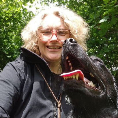 Woman in woods with black dog